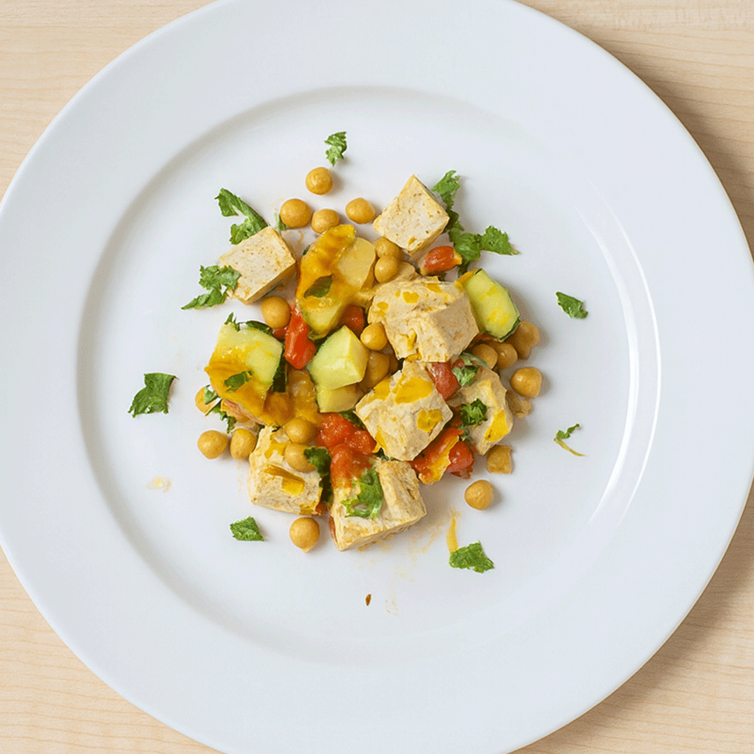 Overhead view of a plate with Tofu, zucchini, onion and garbonzo beans